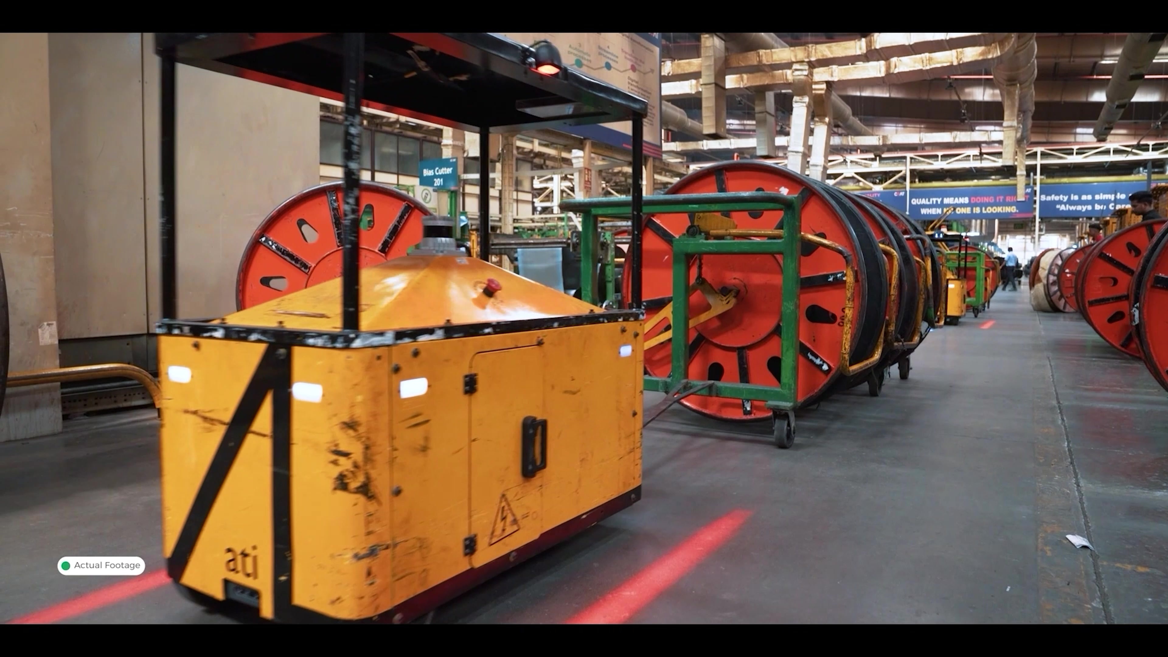An Ati tug towing a train of cable reels down a live aisle at a customer factory.